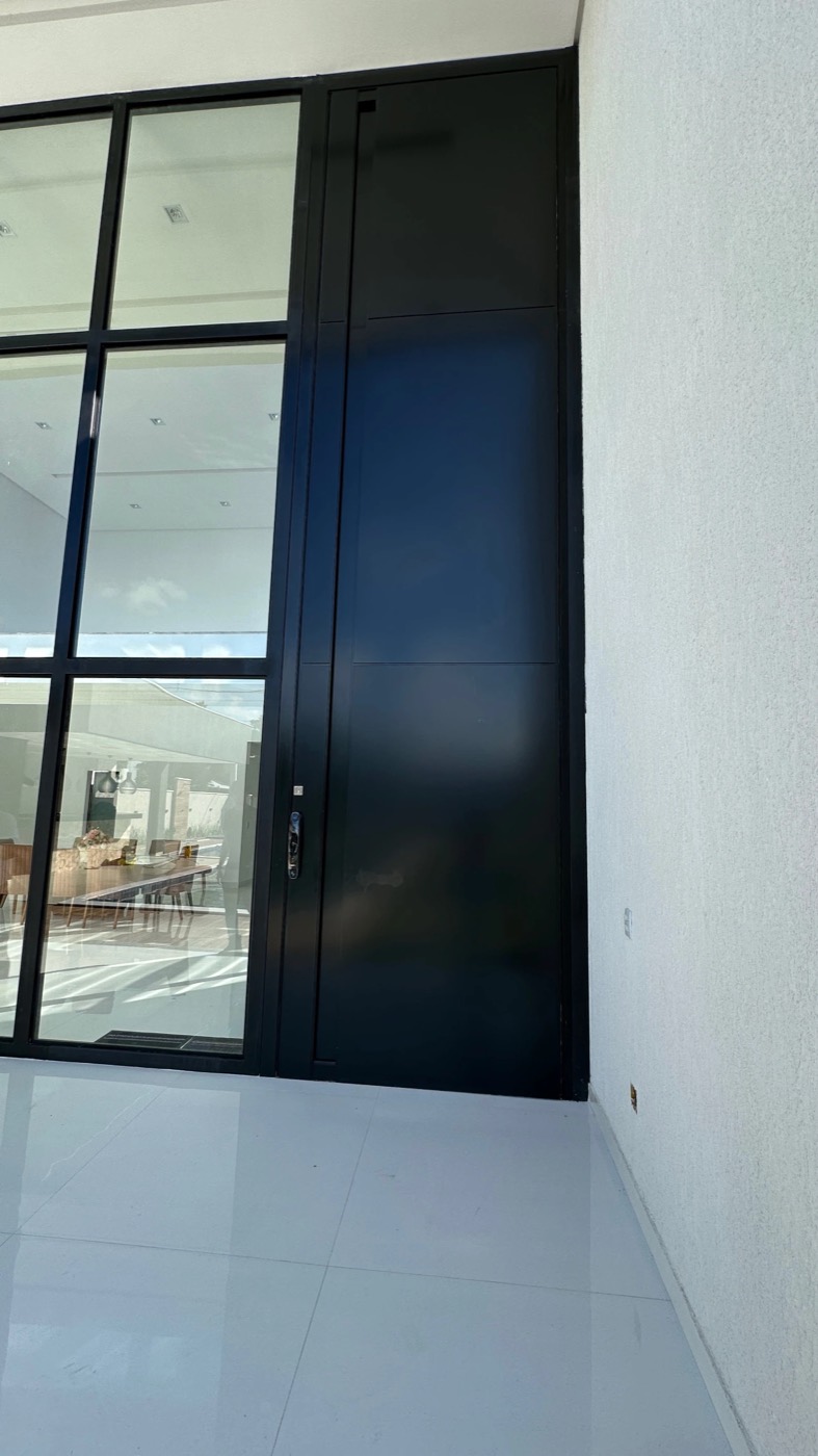 Porta de alumínio preto do piso ao teto, integrada à área de estar